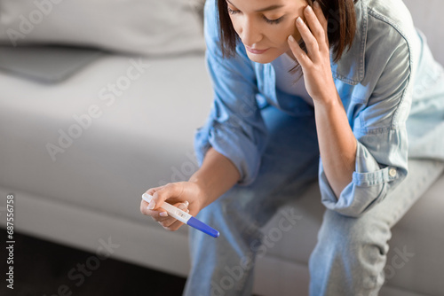 Distraught European young woman looking at positive medical test indoor