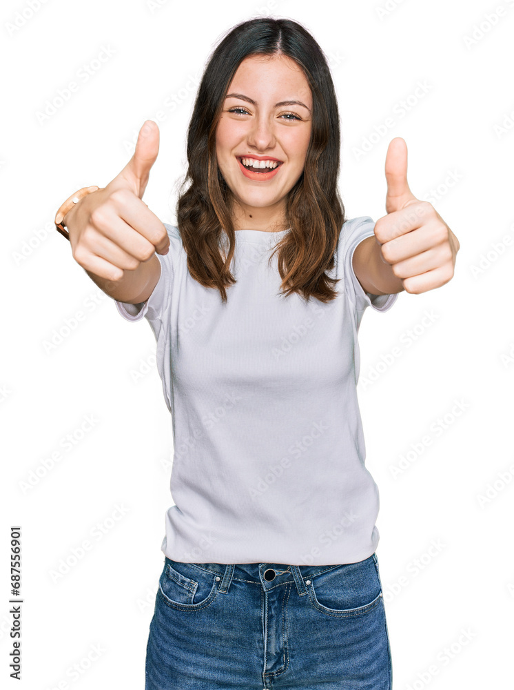 Young beautiful woman wearing casual white t shirt approving doing positive gesture with hand, thumbs up smiling and happy for success. winner gesture. Young beautiful woman wearing casual white t shirt approving doing positive gesture with hand, thumbs up smiling and happy for success. winner gesture.
