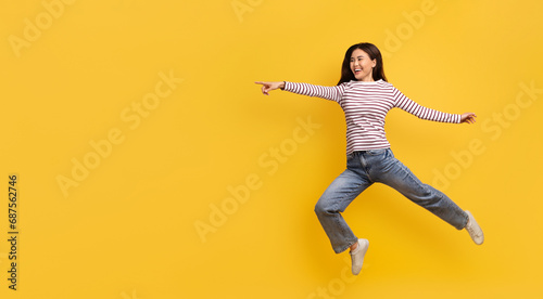 Funny young korean lady jumping in air, pointing copy space