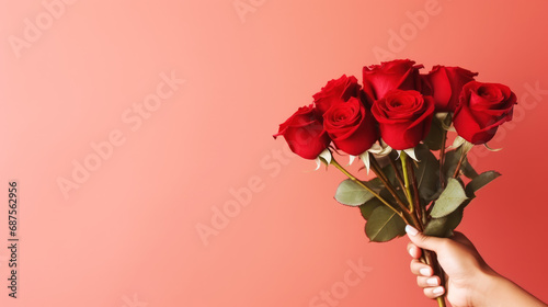 Hand holding bouquet of red roses. Valentine's Day and love concept.