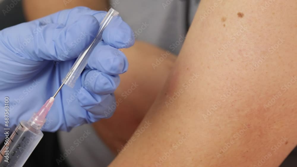 médecin faisant une piqure au bras d'un patient