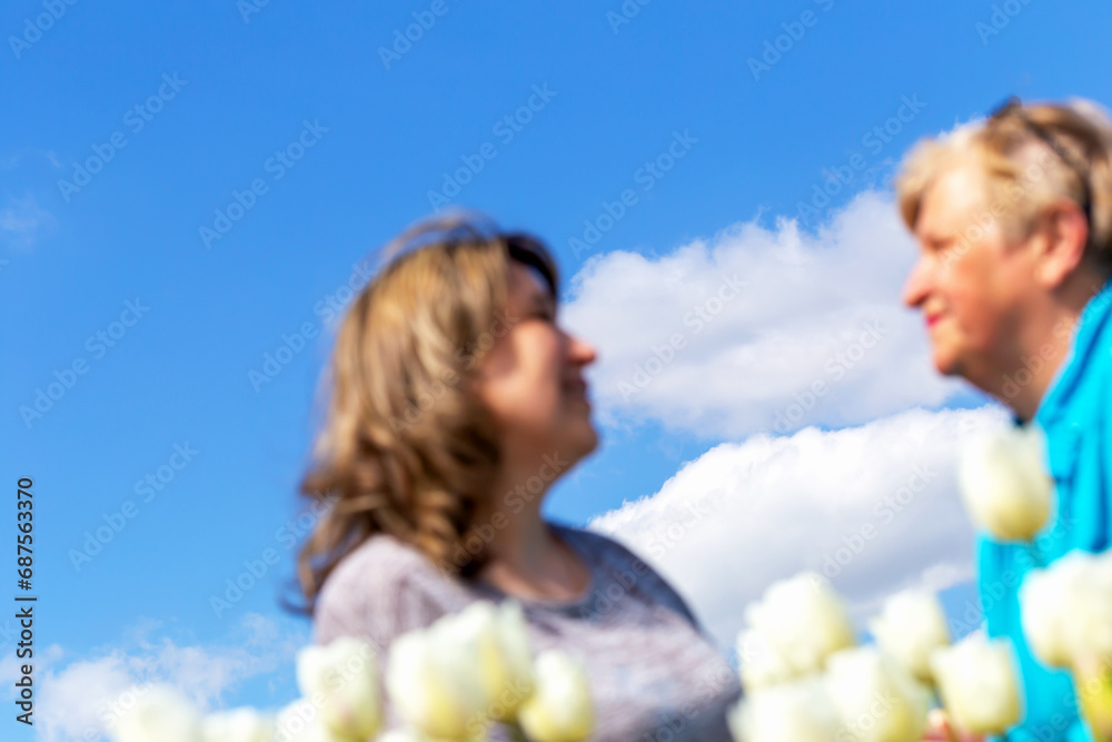 An elderly mother and young daughter look at each other against clear sky. Family relations. Selective focus, defocus, blur An elderly mother and young daughter look at each other against clear sky. Family relations. Selective focus, defocus, blur