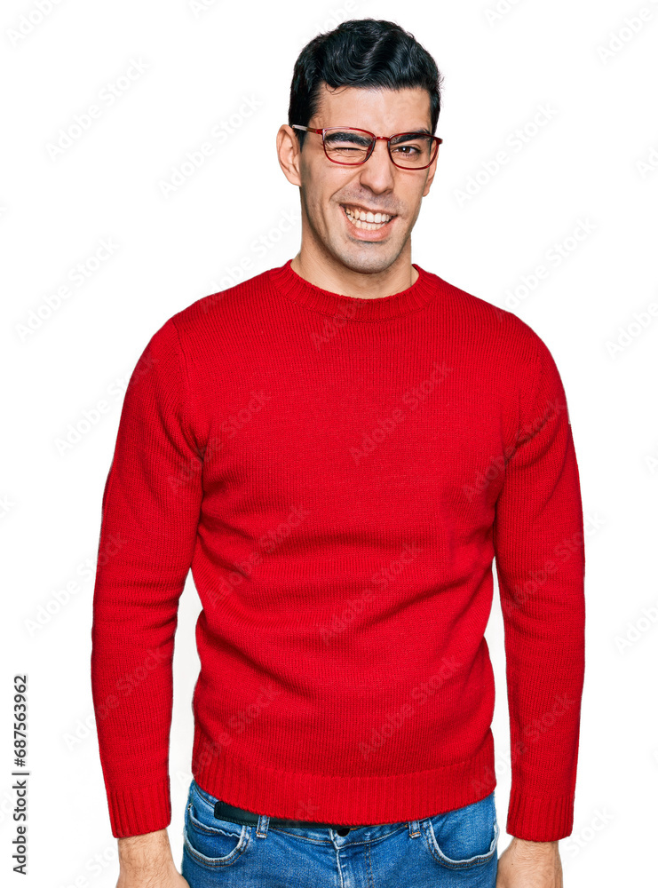 Handsome hispanic man wearing casual clothes and glasses winking looking at the camera with sexy expression, cheerful and happy face. Handsome hispanic man wearing casual clothes and glasses winking looking at the camera with sexy expression, cheerful and happy face.