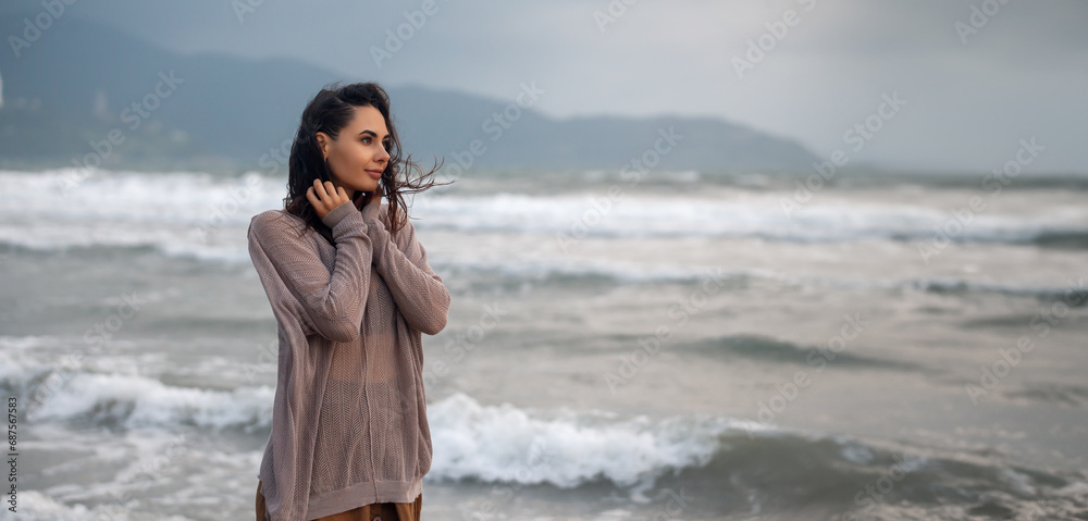 Woman wearing casual clothing enjoying sea storm and water waves of the sea on the beach Woman wearing casual clothing enjoying sea storm and water waves of the sea on the beach
