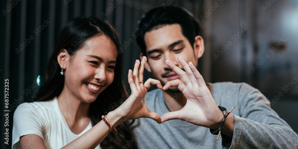 Asian couple hard making heart shape together. Romantic boyfriend girlfriend sharing moment at night. Love and marriage concept Asian couple hard making heart shape together. Romantic boyfriend girlfriend sharing moment at night. Love and marriage concept
