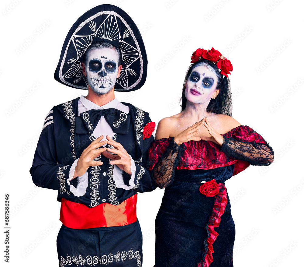 Young couple wearing mexican day of the dead costume over background hands together and fingers crossed smiling relaxed and cheerful. success and optimistic