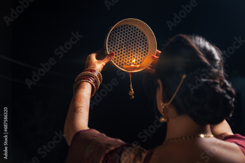 An Indian woman looking at the moon through a sieve during the Karwa Chauth festival. photo