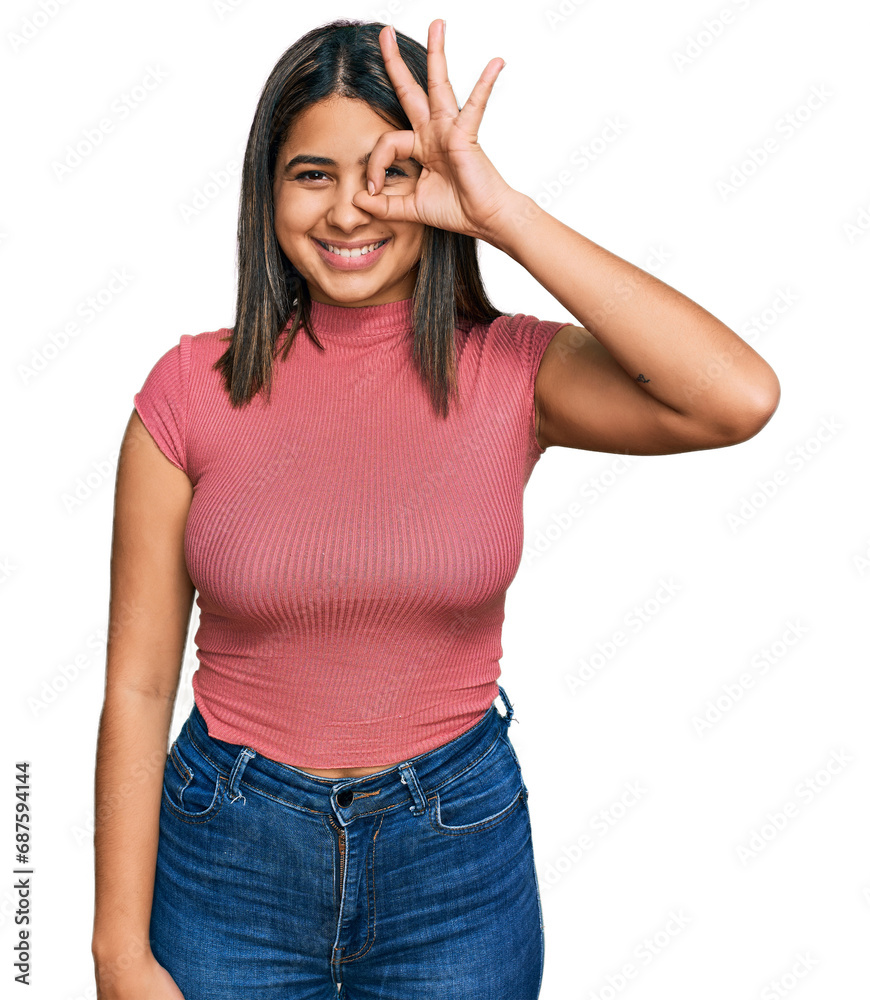 Young hispanic girl wearing casual t shirt doing ok gesture with hand smiling, eye looking through fingers with happy face. Young hispanic girl wearing casual t shirt doing ok gesture with hand smiling, eye looking through fingers with happy face.