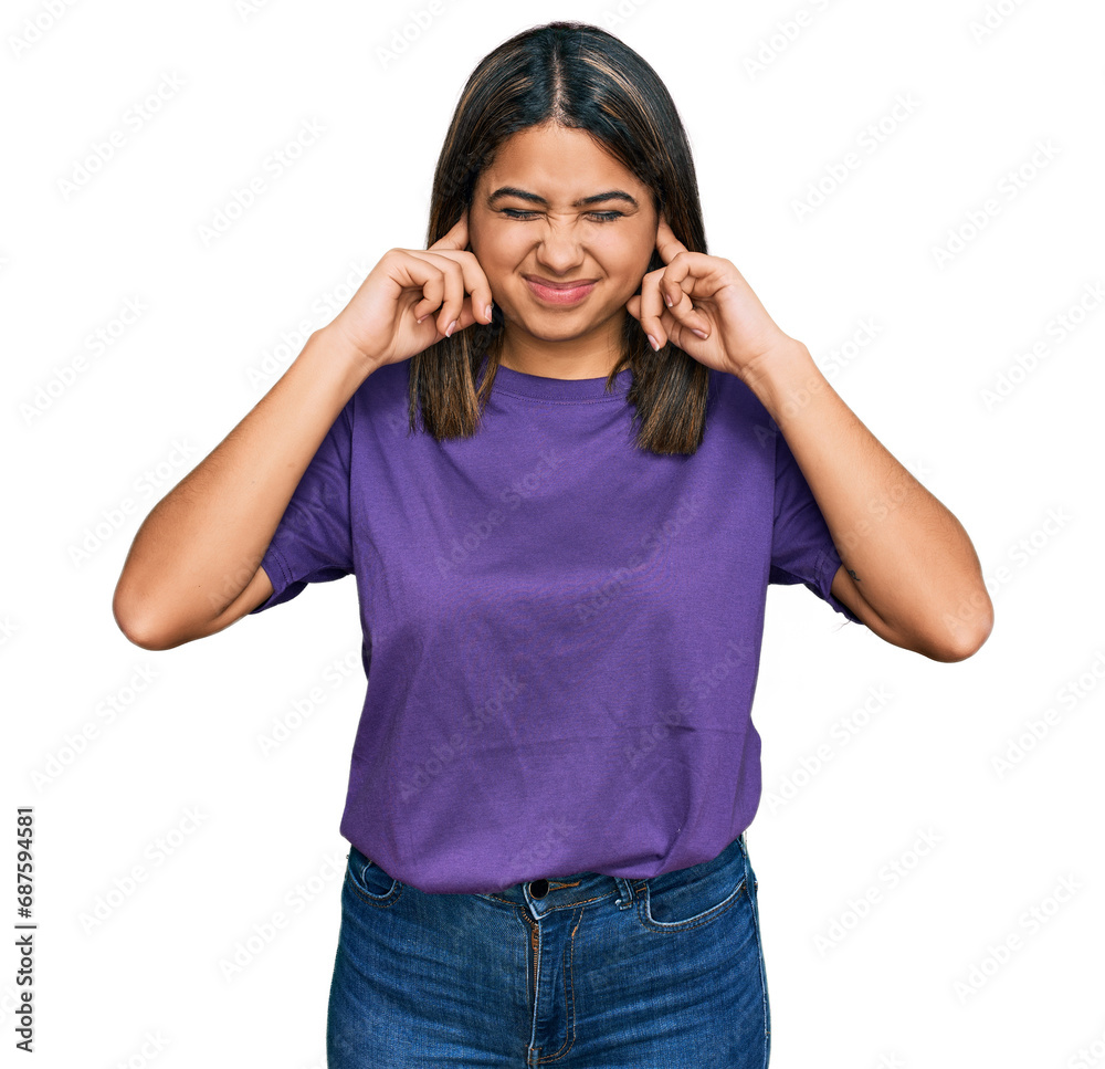 Young hispanic girl wearing casual purple t shirt covering ears with fingers with annoyed expression for the noise of loud music. deaf concept. Young hispanic girl wearing casual purple t shirt covering ears with fingers with annoyed expression for the noise of loud music. deaf concept.