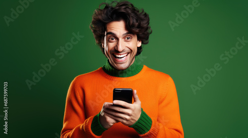 Young man is using a smartphone against green background.