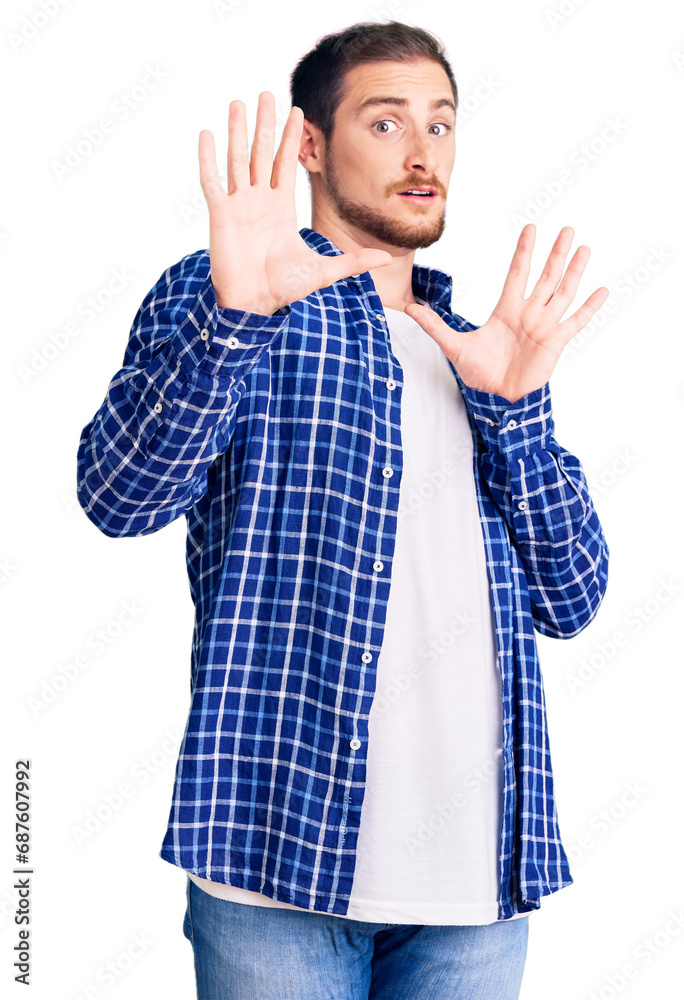 Young handsome caucasian man wearing casual clothes afraid and terrified with fear expression stop gesture with hands, shouting in shock. panic concept. Young handsome caucasian man wearing casual clothes afraid and terrified with fear expression stop gesture with hands, shouting in shock. panic concept.