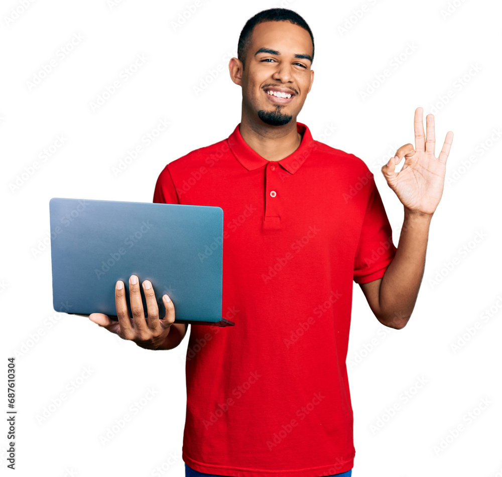 Young african american man working using computer laptop doing ok sign with fingers, smiling friendly gesturing excellent symbol Young african american man working using computer laptop doing ok sign with fingers, smiling friendly gesturing excellent symbol