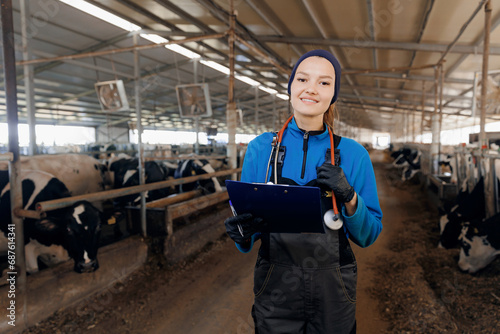Portrait farmer woman veterinarian with clipboard background milk cow in modern barn. Concept vet worker of livestock farm health care cattle