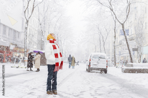 Fototapeta Naklejka Na Ścianę i Meble -  Positive portrait teenage girl in snowfall cityscape