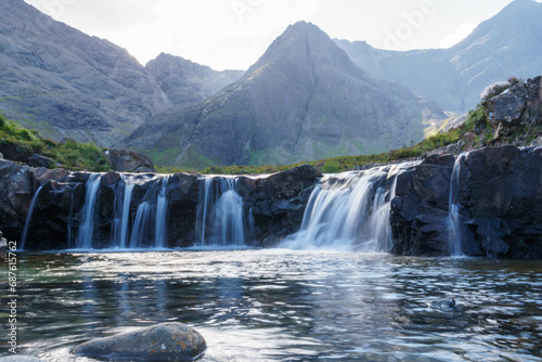 Fairy pool waterfalls and distant mountains in the Isle of Sky. Blurred water and lone foreground rock.