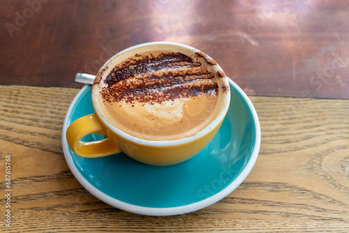 Close-up of a cappuccino in a yellow mug on a blue saucer