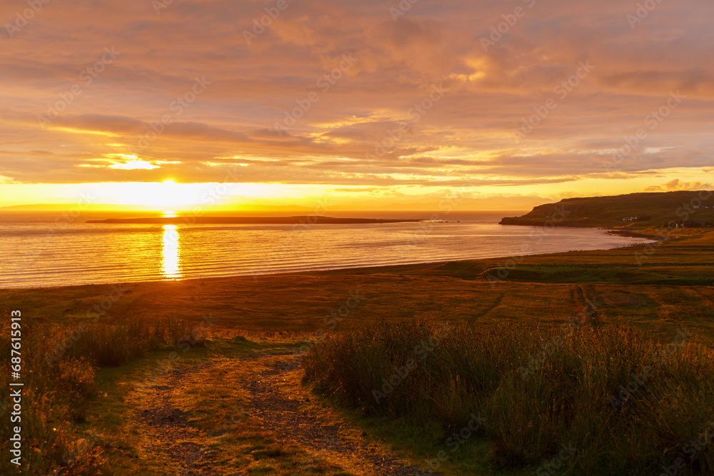 Sunrise on the Isle of Skye over the coastline beyond a winding road