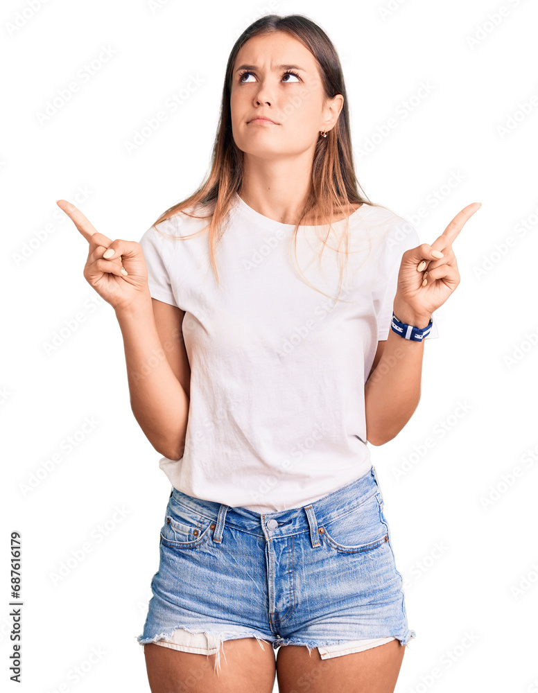Beautiful caucasian woman wearing casual white tshirt pointing up looking sad and upset, indicating direction with fingers, unhappy and depressed.
