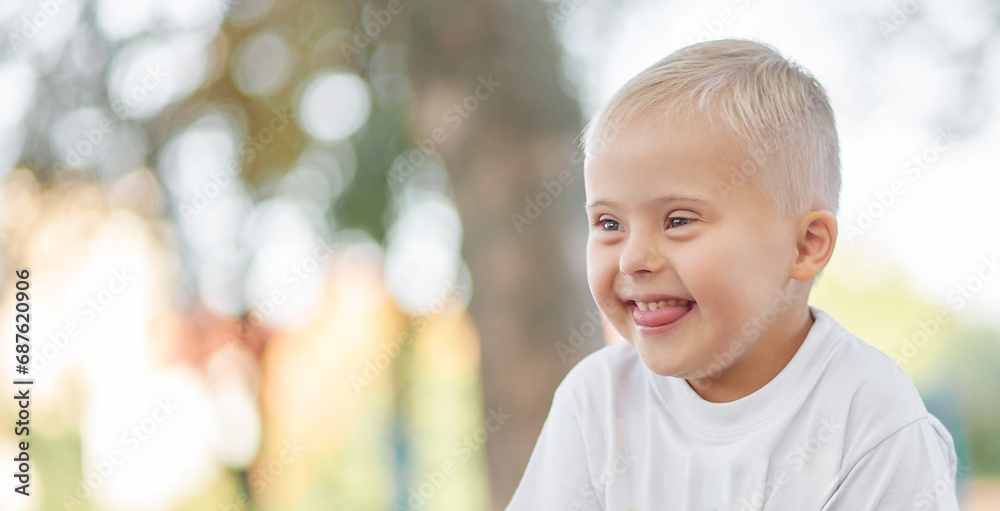 Portrait of a laughing boy with Down syndrome. child outdoors. A handsome boy rejoices.
Portrait of a laughing boy with Down syndrome. child outdoors. A handsome boy rejoices.