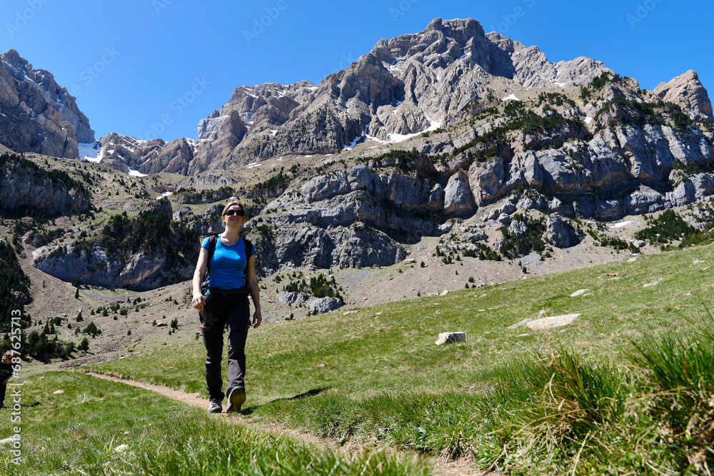 Woman hiking by mountains on sunny day