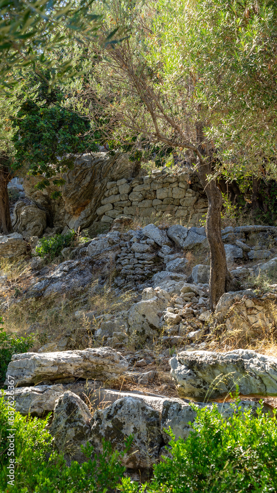 Stone wall in ancient city Amos near town or village of Turunc, Turkey. It was located in Rhodian Peraia in Caria on Mediterranean coast. Vertical image