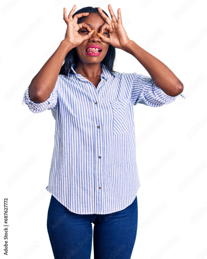 Fototapeta premium Young african american woman wearing casual clothes doing ok gesture like binoculars sticking tongue out, eyes looking through fingers. crazy expression.