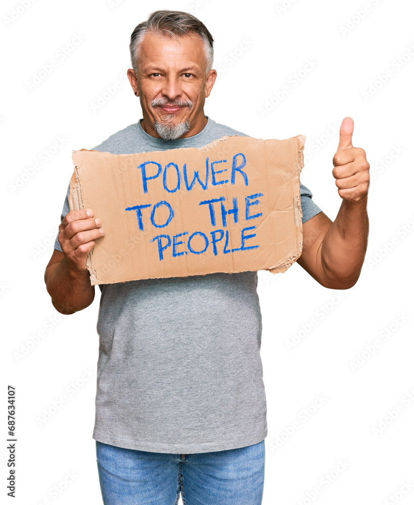 Middle age grey-haired man holding power to the people banner smiling happy and positive, thumb up doing excellent and approval sign Middle age grey-haired man holding power to the people banner smiling happy and positive, thumb up doing excellent and approval sign