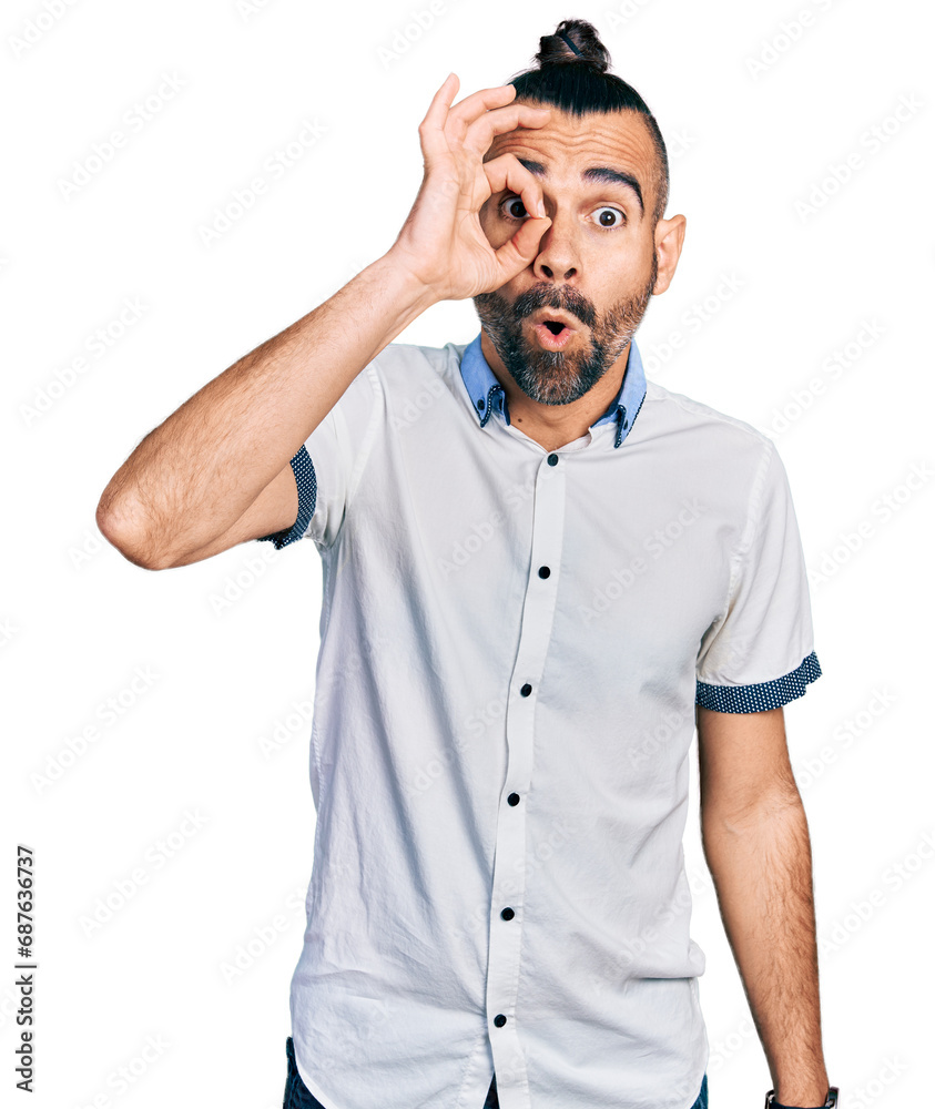 Hispanic man with ponytail wearing casual white shirt doing ok gesture shocked with surprised face, eye looking through fingers. unbelieving expression. Hispanic man with ponytail wearing casual white shirt doing ok gesture shocked with surprised face, eye looking through fingers. unbelieving expression.