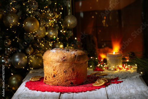 Panettone Christmas cake on a background of a Christmas tree and a burning fireplace