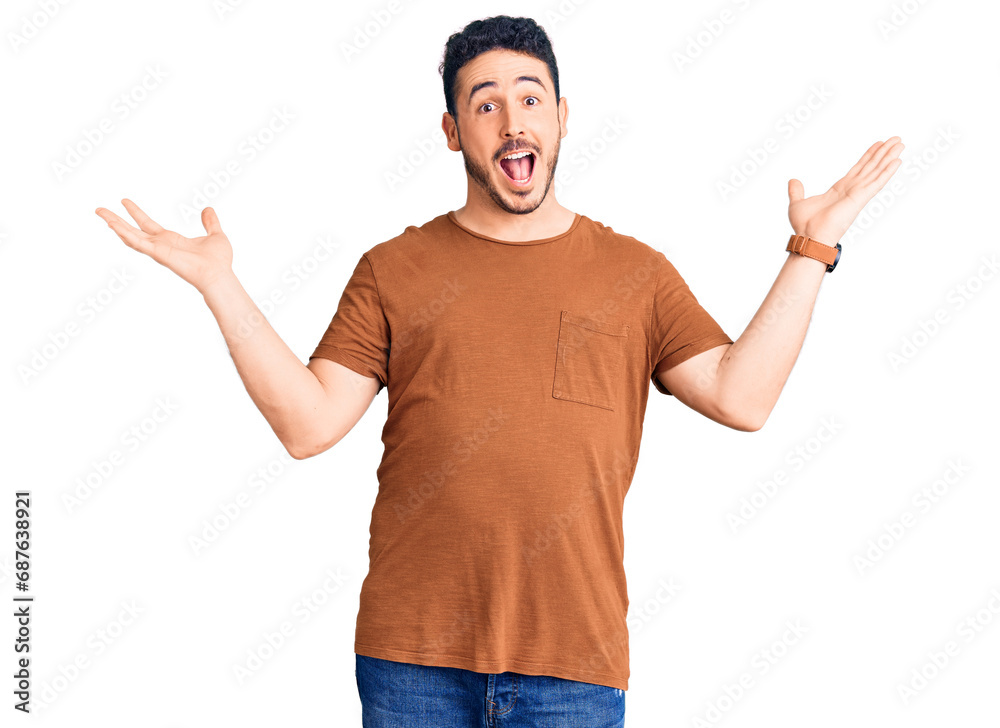 Young hispanic man wearing casual clothes celebrating crazy and amazed for success with arms raised and open eyes screaming excited. winner concept Young hispanic man wearing casual clothes celebrating crazy and amazed for success with arms raised and open eyes screaming excited. winner concept