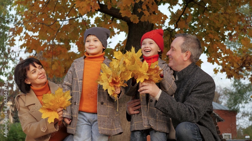 Parents stand with children holding fall leaves in hands on joint vocation