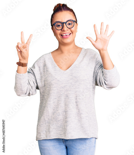 Young latin woman wearing casual clothes showing and pointing up with fingers number seven while smiling confident and happy.