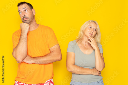 Contemplation of two lovers caucasian 40s couple spouses wife and husband boyfriend and girlfriend looking upwards, planning for future, thoughtful and pensive people isolated in yellow