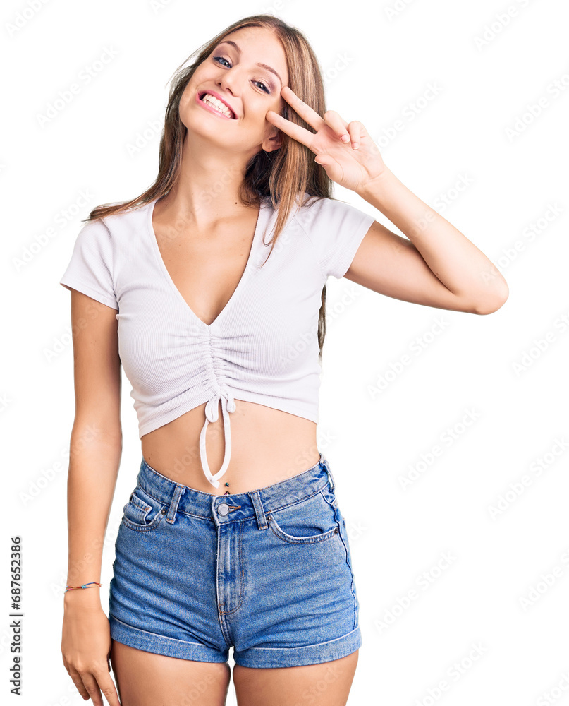 Young beautiful blonde woman wearing casual white tshirt doing peace symbol with fingers over face, smiling cheerful showing victory Young beautiful blonde woman wearing casual white tshirt doing peace symbol with fingers over face, smiling cheerful showing victory