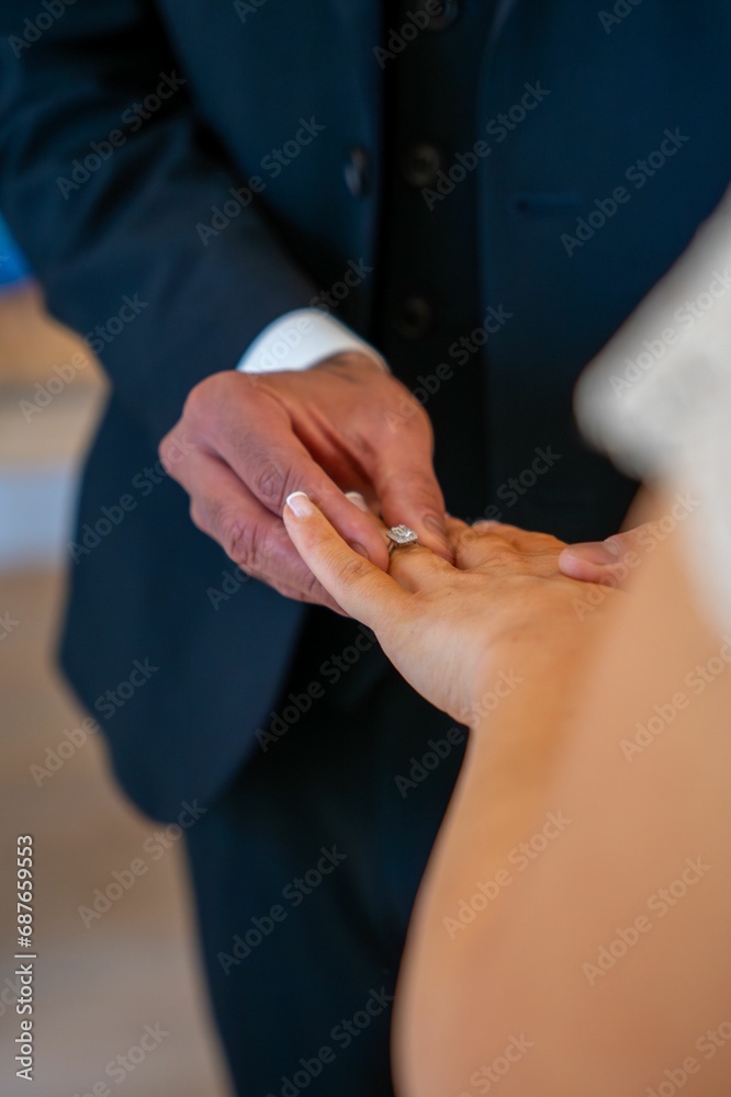 the bride holds her wedding ring as the groom puts on it