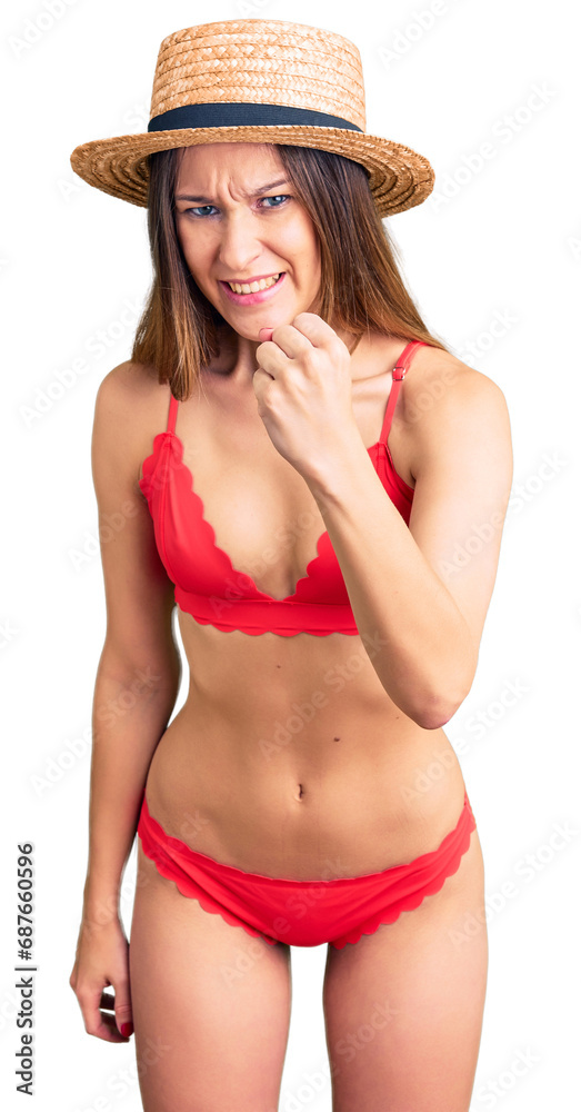 Beautiful brunette young woman wearing bikini angry and mad raising fist frustrated and furious while shouting with anger. rage and aggressive concept. Beautiful brunette young woman wearing bikini angry and mad raising fist frustrated and furious while shouting with anger. rage and aggressive concept.