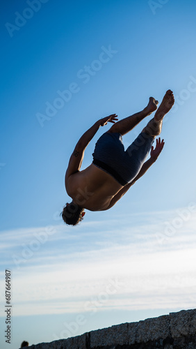 concept about people, lifestyle and sport. A boy performs parkour on the beach. The silhouette against the sunlight