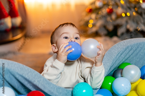 A Joyful Baby Surrounded by Colorful Balloons in a Fun Ball Pit. A baby sitting in a ball pit with balloons