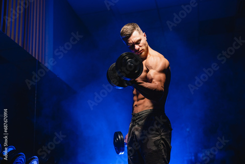 A Strong Man Showing Off His Muscles and Holding Dumbbells. A shirtless man holding a pair of dumbs