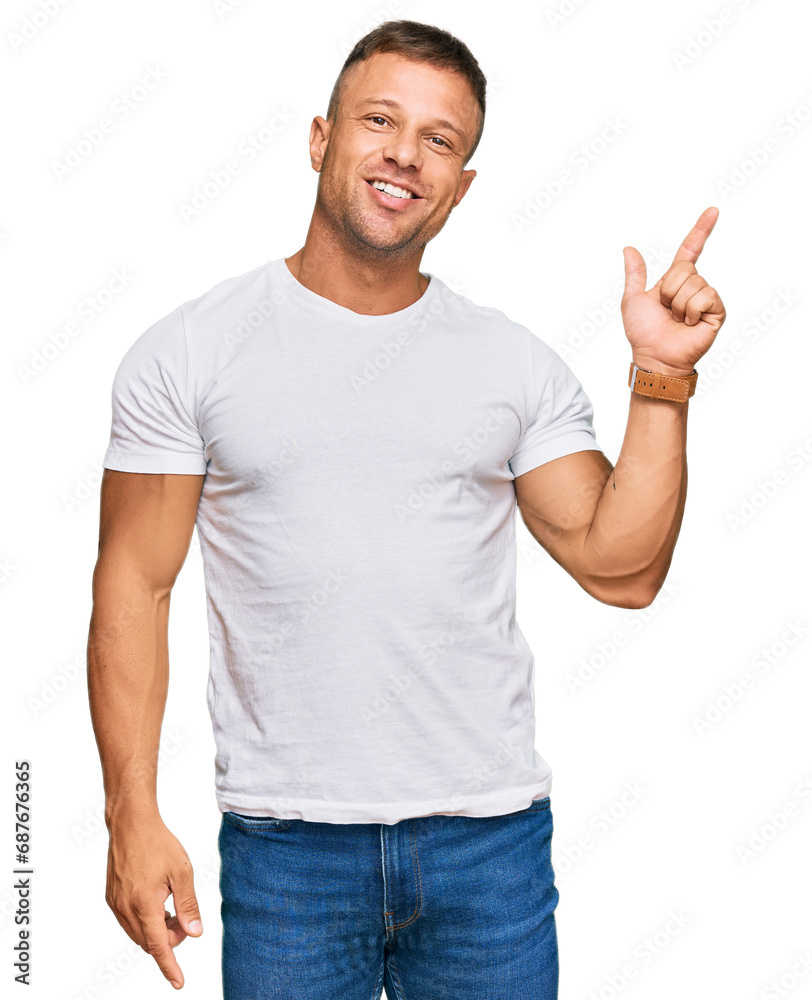 Handsome muscle man wearing casual white tshirt with a big smile on face, pointing with hand finger to the side looking at the camera. Handsome muscle man wearing casual white tshirt with a big smile on face, pointing with hand finger to the side looking at the camera.