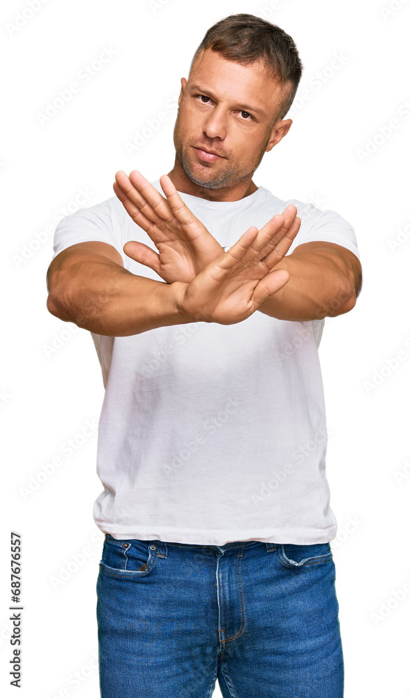 Handsome muscle man wearing casual white tshirt rejection expression crossing arms doing negative sign, angry face Handsome muscle man wearing casual white tshirt rejection expression crossing arms doing negative sign, angry face