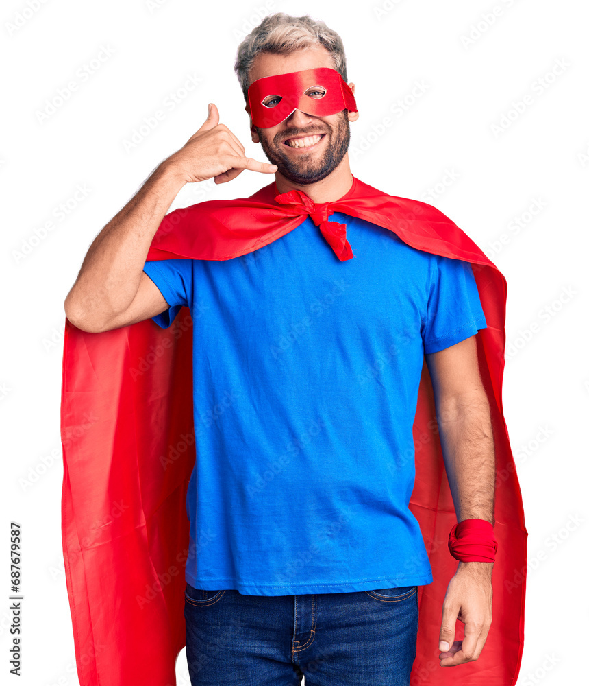 Young blond man wearing super hero custome smiling doing phone gesture with hand and fingers like talking on the telephone. communicating concepts. Young blond man wearing super hero custome smiling doing phone gesture with hand and fingers like talking on the telephone. communicating concepts.