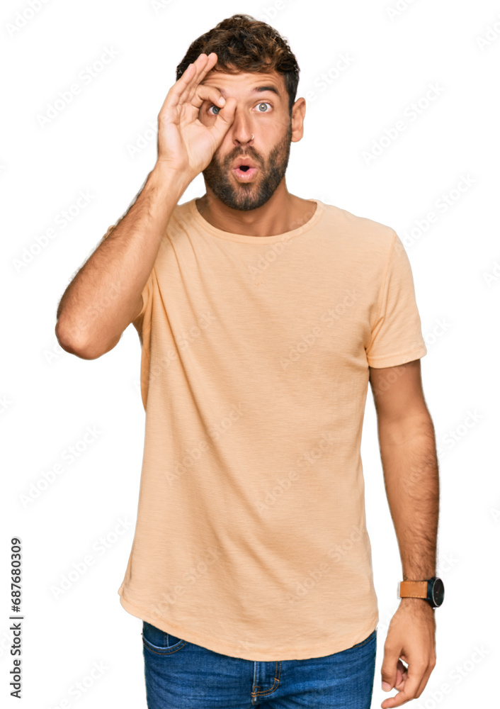 Handsome young man with beard wearing casual tshirt doing ok gesture shocked with surprised face, eye looking through fingers. unbelieving expression. Handsome young man with beard wearing casual tshirt doing ok gesture shocked with surprised face, eye looking through fingers. unbelieving expression.