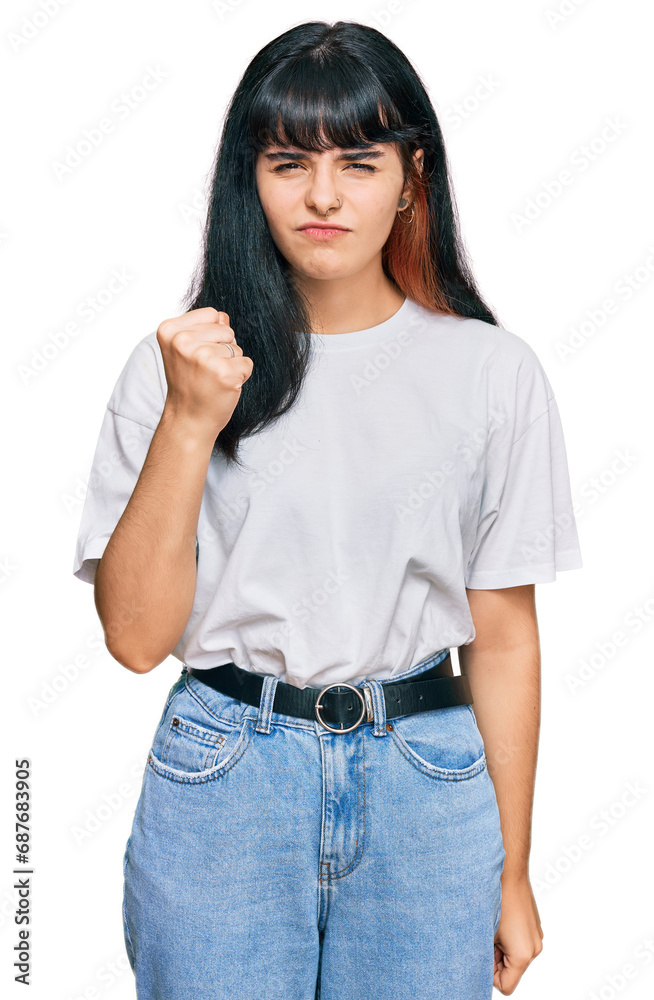 Young hispanic girl wearing casual clothes angry and mad raising fist frustrated and furious while shouting with anger. rage and aggressive concept. Young hispanic girl wearing casual clothes angry and mad raising fist frustrated and furious while shouting with anger. rage and aggressive concept.