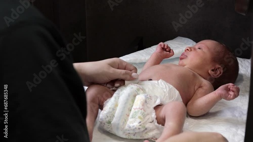 Mother changing diaper on her newborn baby indoors. Little legs of a newborn baby. The child moves his legs. New life. Dry skin of the baby