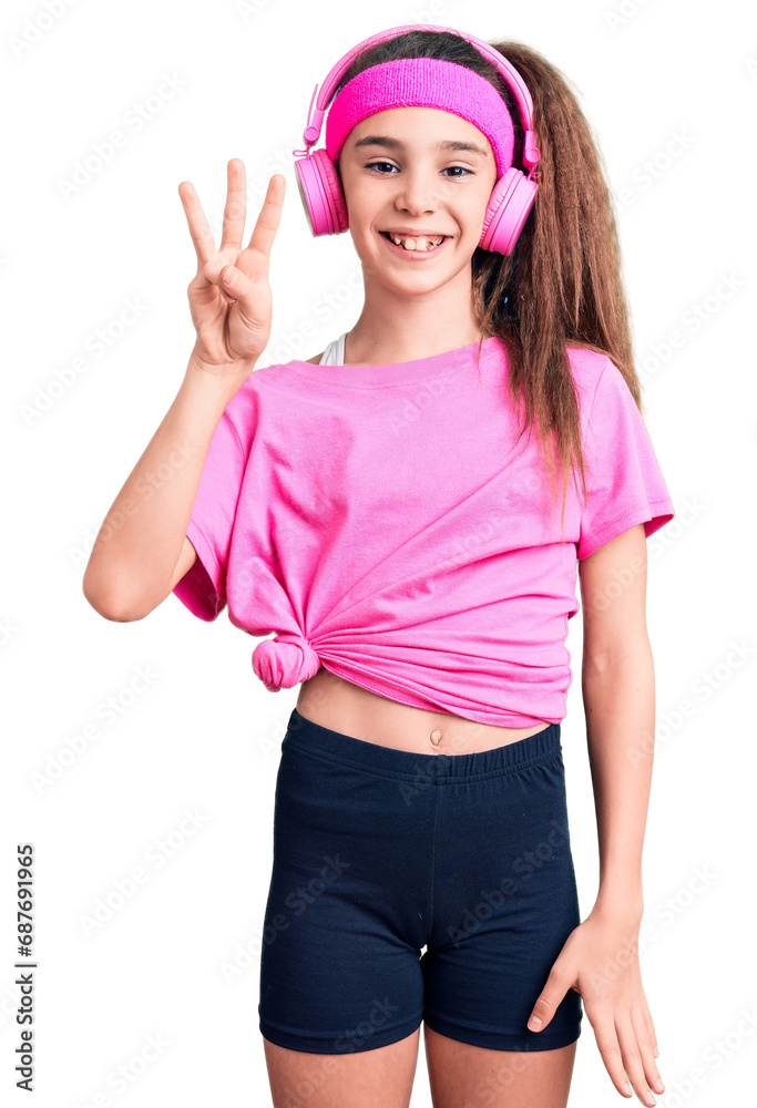 Cute hispanic child girl wearing gym clothes and using headphones showing and pointing up with fingers number three while smiling confident and happy. Cute hispanic child girl wearing gym clothes and using headphones showing and pointing up with fingers number three while smiling confident and happy.