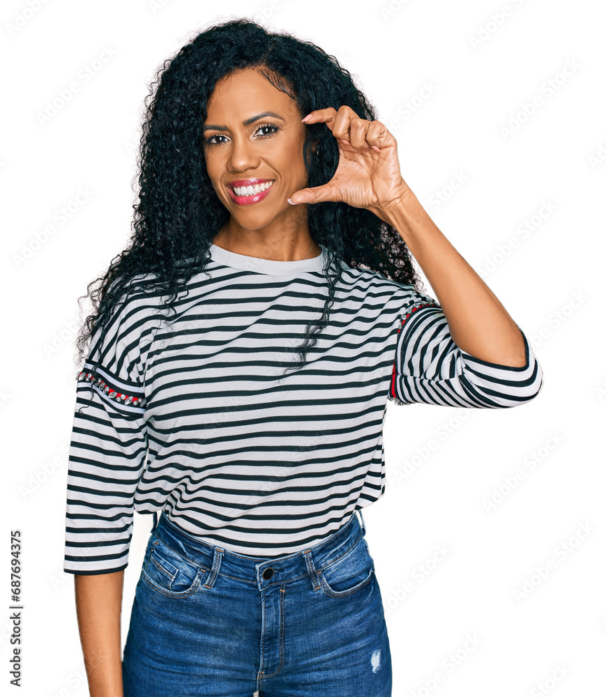Middle age african american woman wearing casual clothes smiling and confident gesturing with hand doing small size sign with fingers looking and the camera. measure concept.