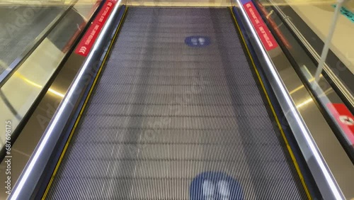 A traveler walks along a moving walkway at the airport. First-person view.