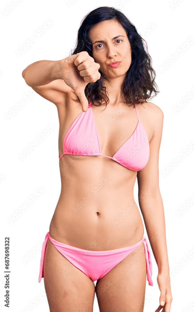 Fototapeta premium Young beautiful hispanic woman wearing bikini looking unhappy and angry showing rejection and negative with thumbs down gesture. bad expression.
