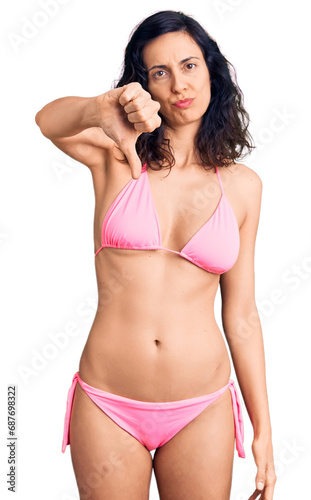 Young beautiful hispanic woman wearing bikini looking unhappy and angry showing rejection and negative with thumbs down gesture. bad expression. © Krakenimages.com